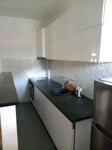 a kitchen with white cabinets and a black counter top at Apartman View in Trebinje