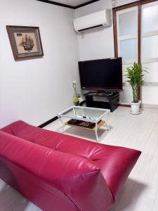 a living room with a red couch and a tv at 金の森民泊 in Osaka