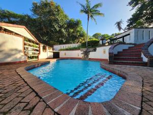 a swimming pool with a brick path around it at Peter Pan Place in Port Edward