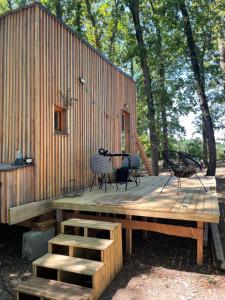 a wooden deck with a table and chairs in front of a building at Tiny housse in Conne-de-Labarde
