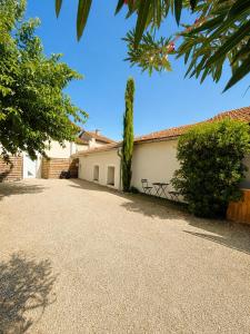 a white building with a tree next to a driveway at Loft, Studio and Love Rooms in Bourg-Saint-Christophe