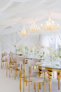 a white dining room with a long table and chairs at Hotel Queen Vera in Mamaia +99 photos