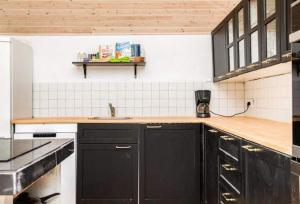 a kitchen with black cabinets and a sink at Coastal Hideout Vacation Home in Bøtø By