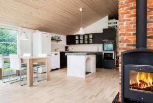 a living room with a fireplace and a table and a kitchen at Coastal Hideout Vacation Home in Bøtø By