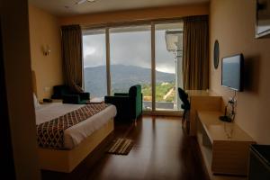 a hotel room with a bed and a large window at Luxe Vista Resort Kodai in Kodaikānāl