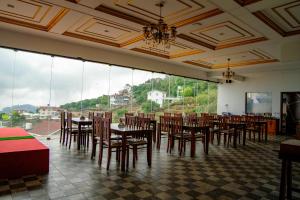 a dining room with tables and chairs and large windows at Luxe Vista Resort Kodai in Kodaikānāl