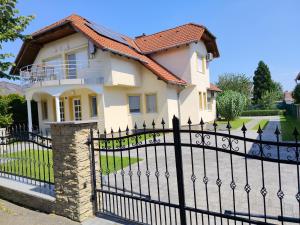 a black fence in front of a house at Abigel Thermal Apartman in Bük