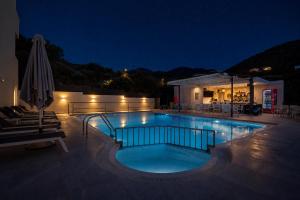 a swimming pool at night with an umbrella at Elpis Studio Apartments in Bali