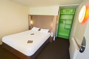 a large white bed in a room with a green door at Campanile Hotel Beauvais in Beauvais +42 photos