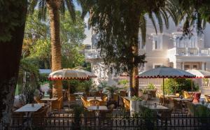 a restaurant with tables and chairs and palm trees at Heritage Hotel Zagreb Dubrovnik in Dubrovnik