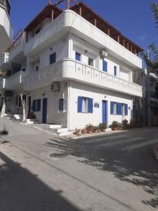 a white building with blue doors on a street at Angelos Rooms in Myrtos