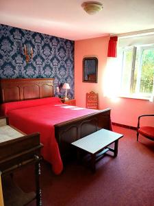 a bedroom with a large red bed with a red blanket at Le Commerce in Bulgnéville