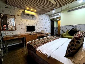 a bedroom with a bed and a desk and a television at Surya Regency in Kāshīpur