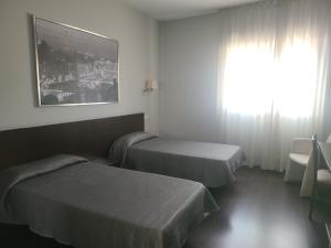 ein Hotelzimmer mit zwei Betten und einem Fenster in der Unterkunft Hostal T4 in Paracuellos de Jarama