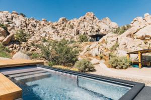 a swimming pool with a rock mountain in the background at Mod West Ranch: 5-acre Boulder Playground in Pioneertown