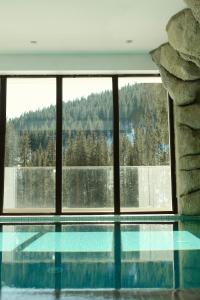 a swimming pool in a house with a large window at Hotel Transalpin in Obarsia-Lotrului