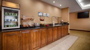 een keuken met houten kasten en een televisie in een kamer bij Best Western Plus Edison Inn in Garner