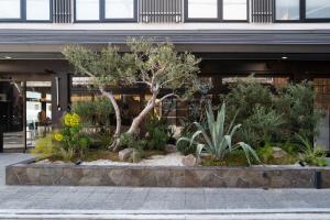 a garden in front of a building with trees and plants at Hotel Glad One Kyoto Shichijo by M's in Kyoto
