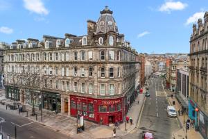 a red double decker bus in front of a building at Henry's Apartment on Commercial Street in Dundee