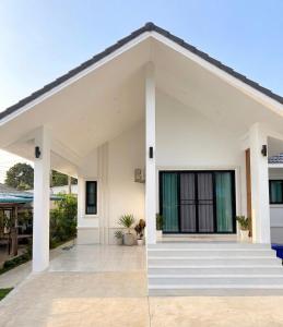 a white house with a porch and stairs at Kulanat House in Chiang Mai