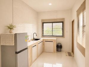a small kitchen with a refrigerator and a window at Kulanat House in Chiang Mai