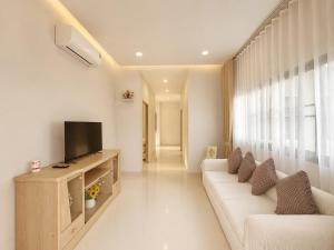a living room with a white couch and a television at Kulanat House in Chiang Mai