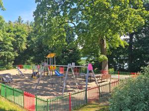 a playground in a park with a fence and trees at Apartament Studio Centrum in Człuchów