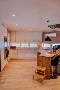 a kitchen with white cabinets and a wooden table at Modern house secluded in nature in Storbukt