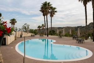 a large swimming pool with palm trees and tables at Kento Resort Hotel in Centuripe