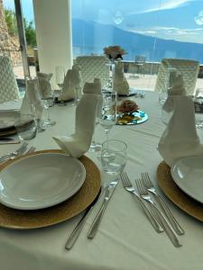 a table with plates and silverware on a white table cloth at Kento Resort Hotel in Centuripe