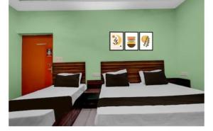 two beds in a room with green walls at Friendly Guest House in Gorakhpur