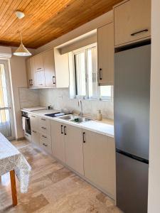 a kitchen with white cabinets and a stainless steel refrigerator at Sea View House B in Péra Mélana