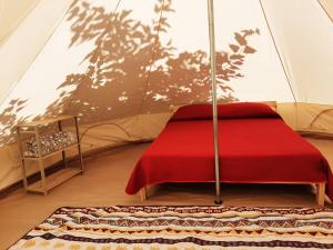 a red bed in a tent with a chair at Glamping Agricampeggio Tognoni in La Sdriscia