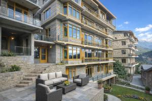 a large apartment building with a patio with couches at Woods Villa Cottages Manali - 1,2,3,4 Bedrooms Luxury Cottages & Villa Available in Manali with Scenic Mountain View, Manali in Manāli