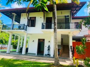 a house with white walls and blue balconies at sunset villa in Hikkaduwa