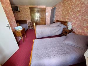 a small room with two beds and two tables at Le Commerce in Bulgnéville