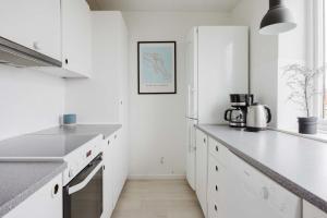 a white kitchen with white cabinets and a sink at Lovely cozy apartment in Søborg +21 photos