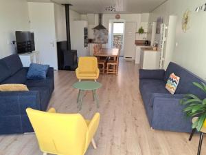 a living room with a blue couch and yellow chairs at La belle étoile in Saugues +5 photos
