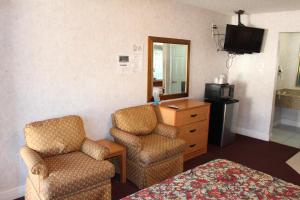 Habitación de hotel con 1 cama, 2 sillas y TV en Highlander Motor Inn Atlantic City, en Galloway