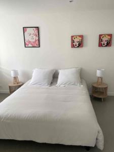 a bedroom with a white bed with three pictures on the wall at appartement la pause coté mer in Santec