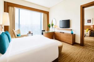 a hotel room with a large bed and a television at Hotel Meenakachi Resort in Brahmapur