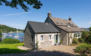 a small house on the shore of a body of water at Otterpoint Waterfront & Pool Retreat in Tayvallich