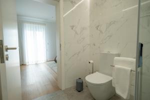 a white bathroom with a toilet and a glass door at Ponta do Pargo Village - By WeHostMadeira in Ponta do Pargo
