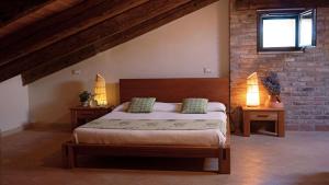 a bedroom with a bed with two lamps and a brick wall at Agriturismo Monte degli Aromi in Villaga