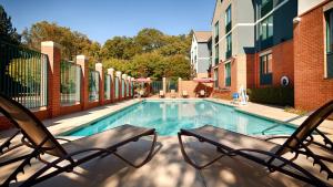 a swimming pool with two chairs in front of a building at Best Western Plus Roswell/Alpharetta in Roswell