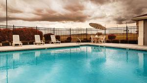 a swimming pool with chairs and a table and an umbrella at Best Western Inn and Suites Copperas Cove in Copperas Cove