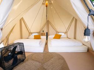 two beds in a tent with a rug at Kampaoh El Palmar in El Palmar
