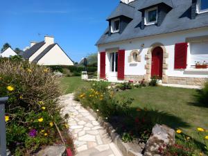 a house with red shutters and a garden with flowers at Bénodet Chambre D'hôtes Les Sauges in Bénodet