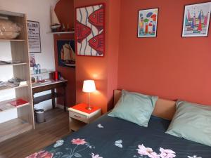 a bedroom with an orange wall with a bed and a desk at Bénodet Chambre D'hôtes Les Sauges in Bénodet