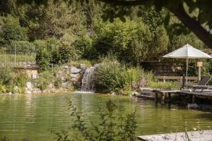 a pond with an umbrella next to a waterfall at VAYA Lechtal in Elbigenalp